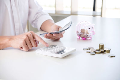 Midsection of businesswoman calculating paper currency in office