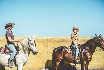 Couple riding horses by retaining wall