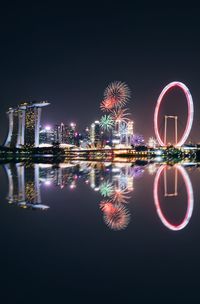 Illuminated city by river at night