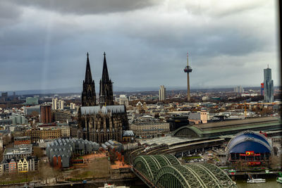 Aerial view of buildings in city against cloudy sky