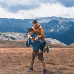 Full length of young man standing on mountain against sky