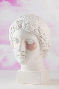 Hydrogel pink patches on the plaster head of aphrodite on a pink background. beauty concept.