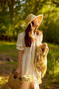 Side view of young woman standing against trees