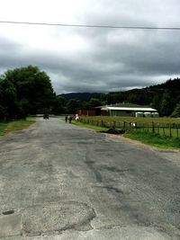 Cars on road against cloudy sky