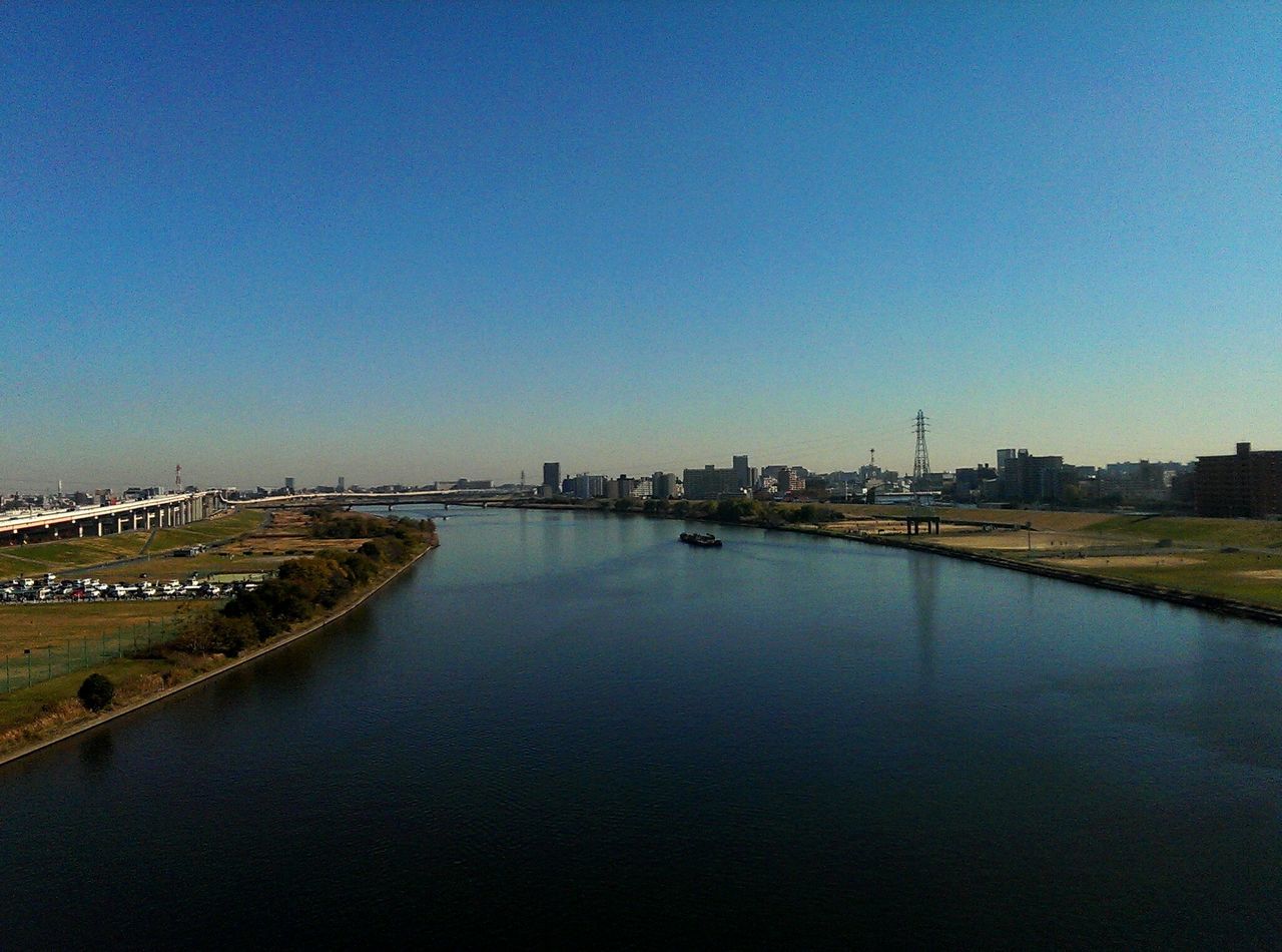 clear sky, copy space, water, built structure, blue, architecture, river, building exterior, reflection, waterfront, tranquility, tranquil scene, connection, nature, lake, outdoors, mid distance, scenics, no people, day