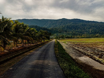 Road leading towards mountains against sky