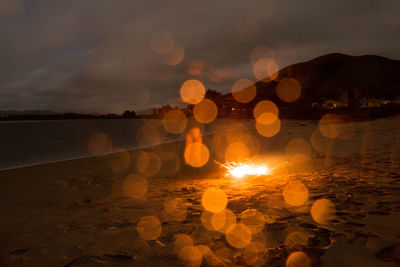 Illuminated lights against sky at sunset