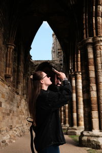 Low angle view of young woman standing against wall