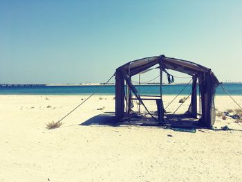 Pier on sandy beach against clear blue sky