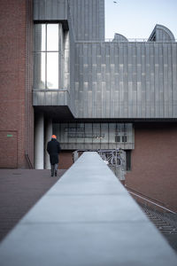 Rear view of man walking by building in city