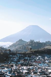 Aerial view of townscape by mountain against sky