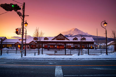 Snow covered houses against clear sky during sunset