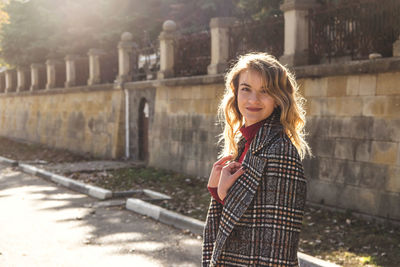 Portrait of young woman with blond hair standing on street