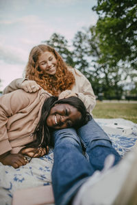 Happy teenage girl sleeping on female friends lap at park