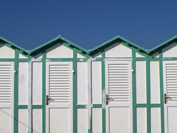 Green beach huts against blue sky