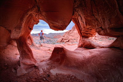 Rear view of man standing on rock seen from cave at valley of fire state park