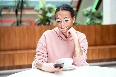 Man using mobile phone while sitting on table