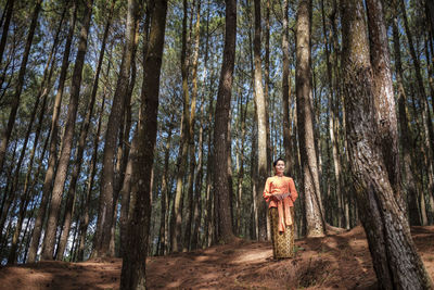 Woman standing against trees in forest