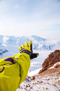 Low section of person on snow covered mountain against sky