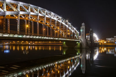 Illuminated bridge over river at night