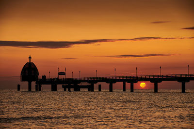 Silhouette of bridge over sea during sunset