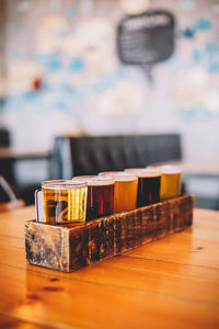 Close-up of various beer glasses in wooden tray on table