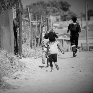 Rear view of mother and daughter walking on road