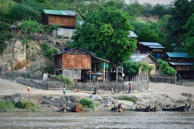 Houses on riverbank against trees