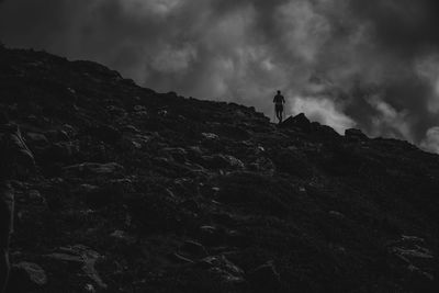 Low angle view of man standing on rock against sky