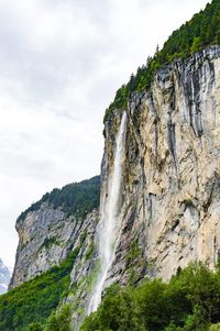 Low angle view of waterfall on cliff against sky