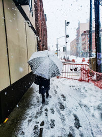 Man walking on wet street in city during winter