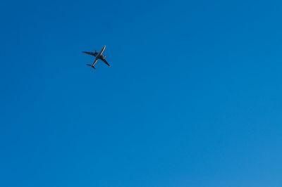 Low angle view of airplane against clear blue sky