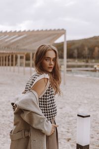 Portrait of young woman standing against sky
