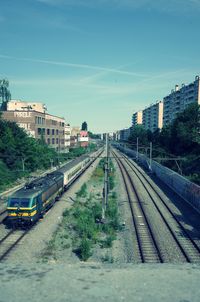 Train on railroad tracks in city against sky