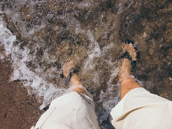 Low section of man standing by sea