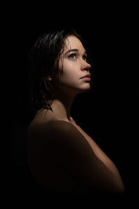 Portrait of young woman against black background