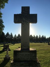 Cross sign on cemetery against sky