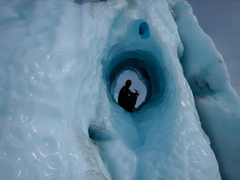 Silhouette man sitting in ice cave