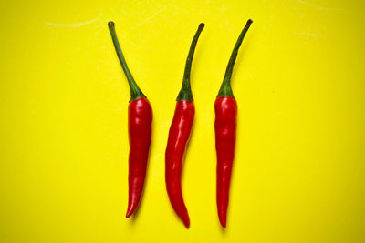 Close-up of red chili peppers against yellow background