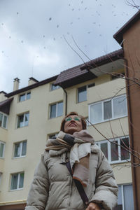 Side view of woman standing against building