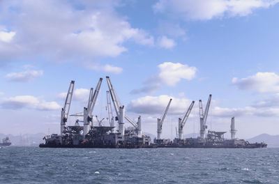 Cranes at commercial dock against sky