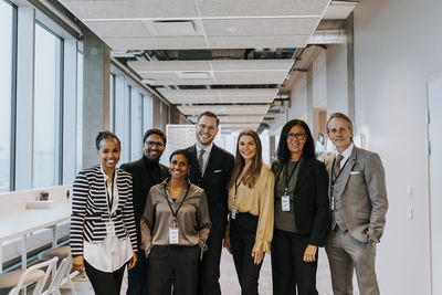 Portrait of smiling multiracial colleagues standing in corridor