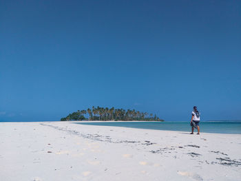 Woman on beach against clear blue sky