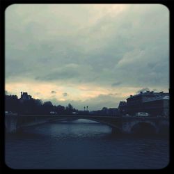 Bridge over river against cloudy sky