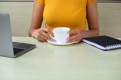 Midsection of woman using laptop on table