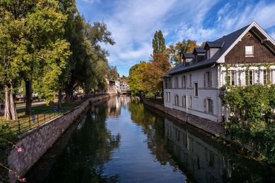 Canal amidst trees and buildings against sky