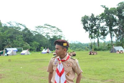 Young man standing on field against sky