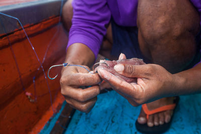 Low section of man removing fish from hook in boat