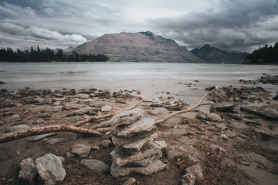 Stack of stones near by lake shore with mountain in background.