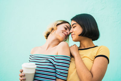 Side view of smiling lesbian couple romancing against wall